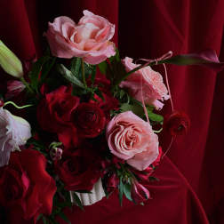 Bouquet of pink and red roses with a lily bud in a white vase