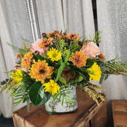 Mixed bouquet of yellow and peach flowers in a white vase