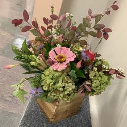 Mixed bouquet with pink and purple flowers in a wooden box