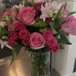 Vase arrangement of pink roses, white alstroemeria, and green button mums in a clear glass cylinder