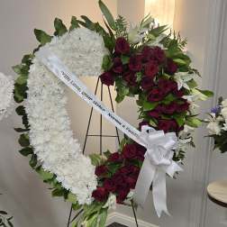 Heart-shaped funeral wreath of white chrysanthemums and red roses on an easel