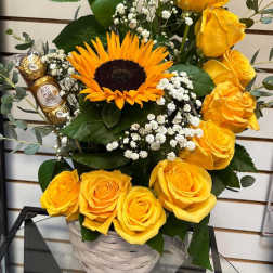 Yellow roses and a sunflower in a white basket with chocolates
