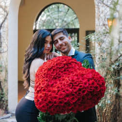 Couple holding a large bouquet of red roses