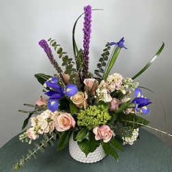 Mixed bouquet of pink roses and purple irises in a white vase