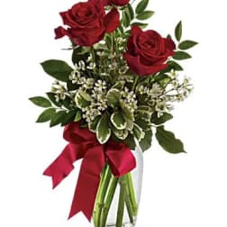 Red roses in a glass vase with a red ribbon