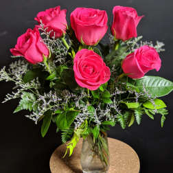 Pink roses arranged in a clear glass vase with greenery