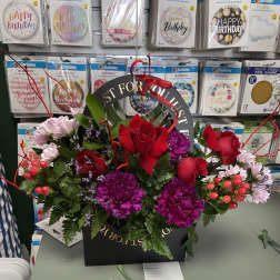 Birthday flower arrangement in a black gift box with red roses and purple blooms