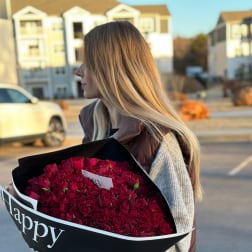 Woman holding a large bouquet of red roses wrapped in black paper