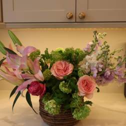 Basket arrangement with pink roses, calla lilies, and lavender blooms