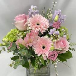 Pink and lavender flowers arranged in a clear glass vase