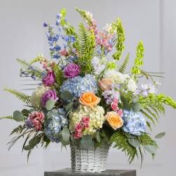 Mixed bouquet in a white wicker basket with roses and hydrangeas