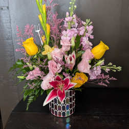 Mixed bouquet with yellow roses, pink lilies, and a mosaic vase