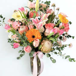 Pink and peach mixed bouquet in a glass vase with a ribbon