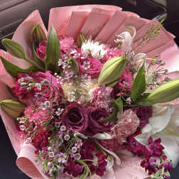 Pink and white bouquet with roses, lilies, and carnations wrapped in pink paper