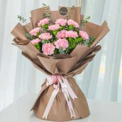 Pink carnation bouquet wrapped in brown paper with a ribbon