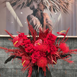 Large red floral arrangement in a black vase with roses and anthuriums