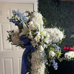 Large white floral standing spray with blue ribbon and blue accents