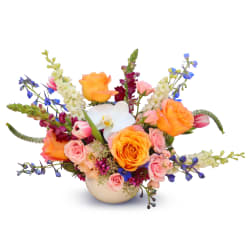Colorful bouquet of roses, orchids, and blue flowers in a round vase
