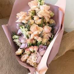 Bouquet of peach and lavender roses wrapped in pink paper