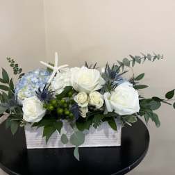 White and blue floral arrangement in a rectangular wooden box