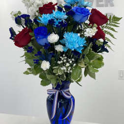 Red and blue roses with white and blue flowers in a cobalt vase