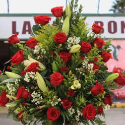Tall arrangement of red roses and lilies in a glass vase