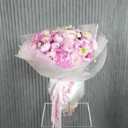 Pink bouquet of peonies wrapped in white paper with ribbon