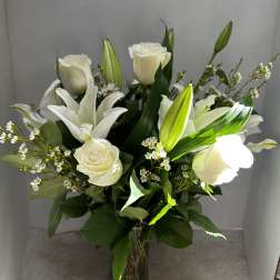 White roses and lilies arranged in a clear glass vase