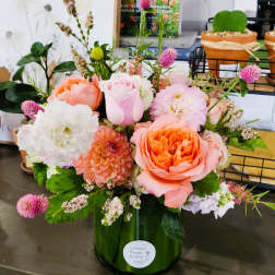 Mixed pink and peach flowers arranged in a green glass vase