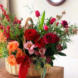 Basket arrangement of red and peach roses with tulips and berries