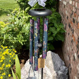 Black wind chime with a white bow hanging outdoors