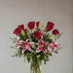 Red roses and pink lilies arranged in a clear glass vase