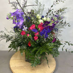 Tall mixed bouquet with purple, pink, and white flowers in a glass vase