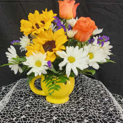 Bouquet of sunflowers, white daisies, and orange roses in a yellow mug vase