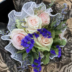 Bouquet of pale pink roses with purple filler flowers and white mesh wrap