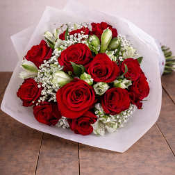 Bouquet of red roses with white filler flowers wrapped in white paper