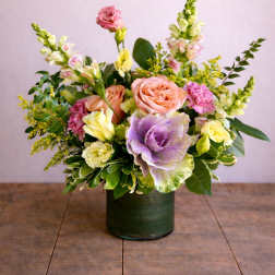 Pastel floral arrangement in a dark green vase with roses and snapdragons