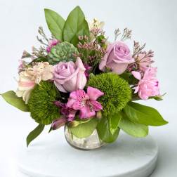 Pink and lavender bouquet in a clear glass vase with green accents