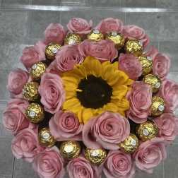 Pink roses and a sunflower arranged with gold-wrapped chocolates