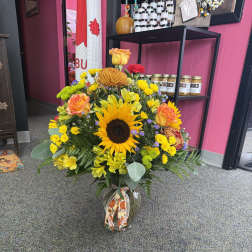 Mixed bouquet with sunflowers, roses, and chrysanthemums in a glass vase