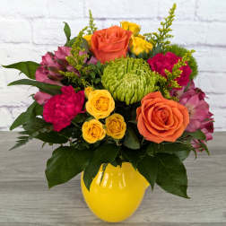 Mixed bouquet of roses, chrysanthemums, and pink blooms in a yellow vase