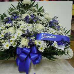 White and purple funeral spray with a blue ribbon reading Grandma