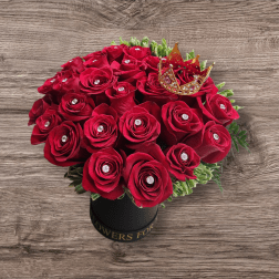 Red rose bouquet in a black hatbox with a small crown topper