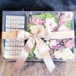 Gift box with pink and white flowers, roses, and folded cash tied with a ribbon