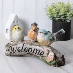 Decorative welcome sign with three bird figurines and a small pink flower
