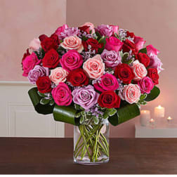 Bouquet of pink, red, and lavender roses in a clear glass vase