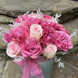 Pink and white rose bouquet in a gray container with a pink ribbon