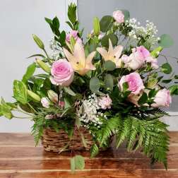 Pink roses and lilies arranged in a wicker basket