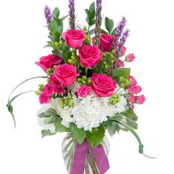 Pink roses and white hydrangeas in a glass vase with a ribbon