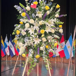 Large standing floral spray with white lilies, yellow roses, and purple flowers